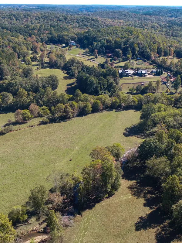 Birds-eye perspective of a large field of farmland surrounded by trees