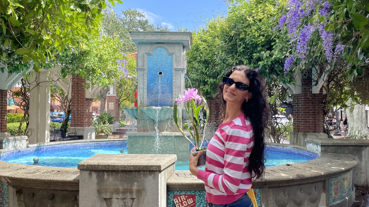 Maressa holding an orchid plant in front of a fountain