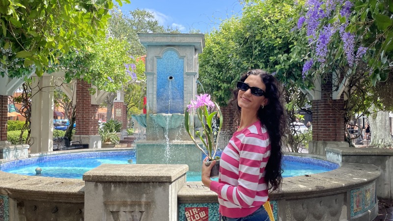 Maressa holding an orchid plant in front of a fountain